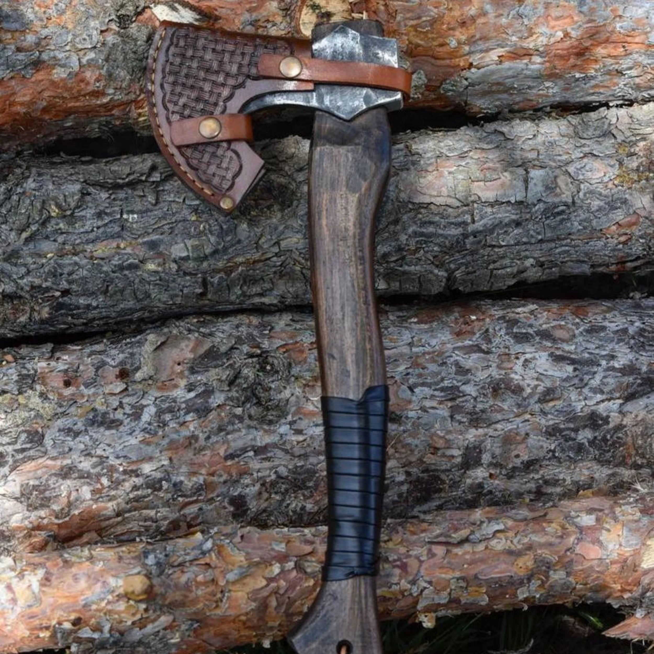 Craftman kampçı baltası işlemeli deri kılıfıyla, odun tomrukları önünde dikey